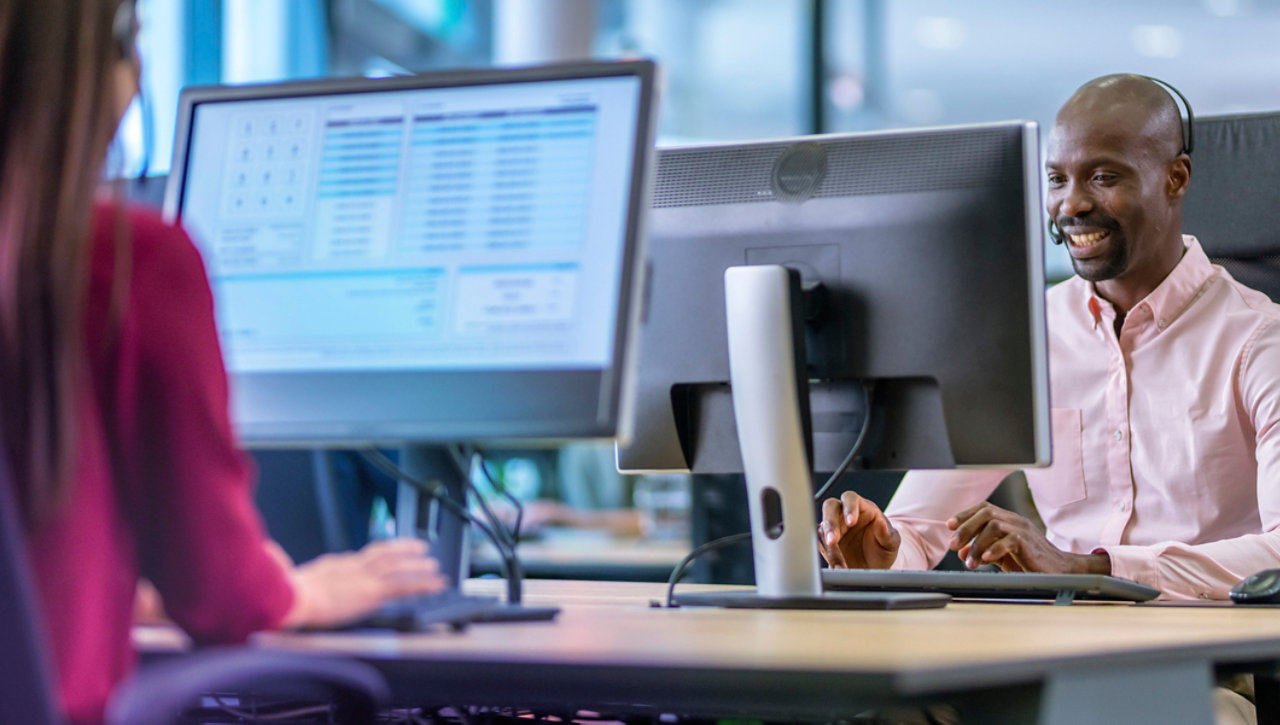 smiling man and woman on computers in office