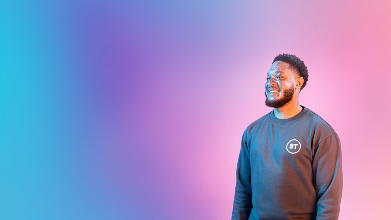 bearded man smiling infront of multicoloured cloud background