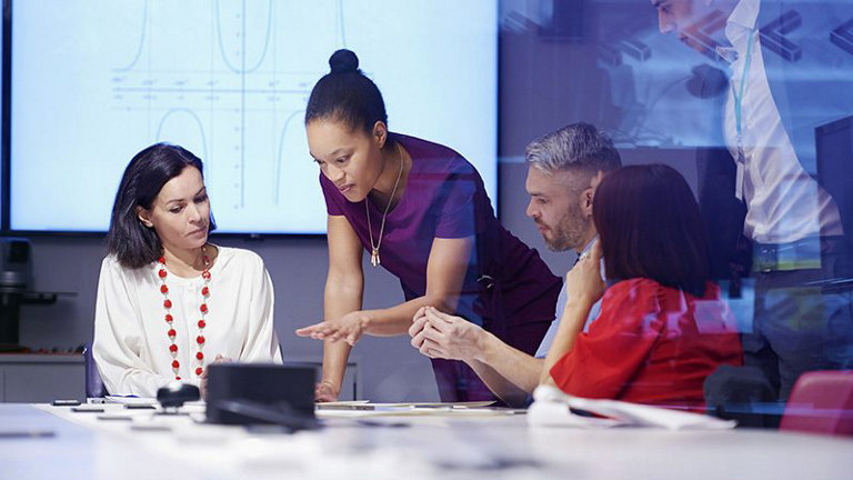 Colleagues talking at a desk