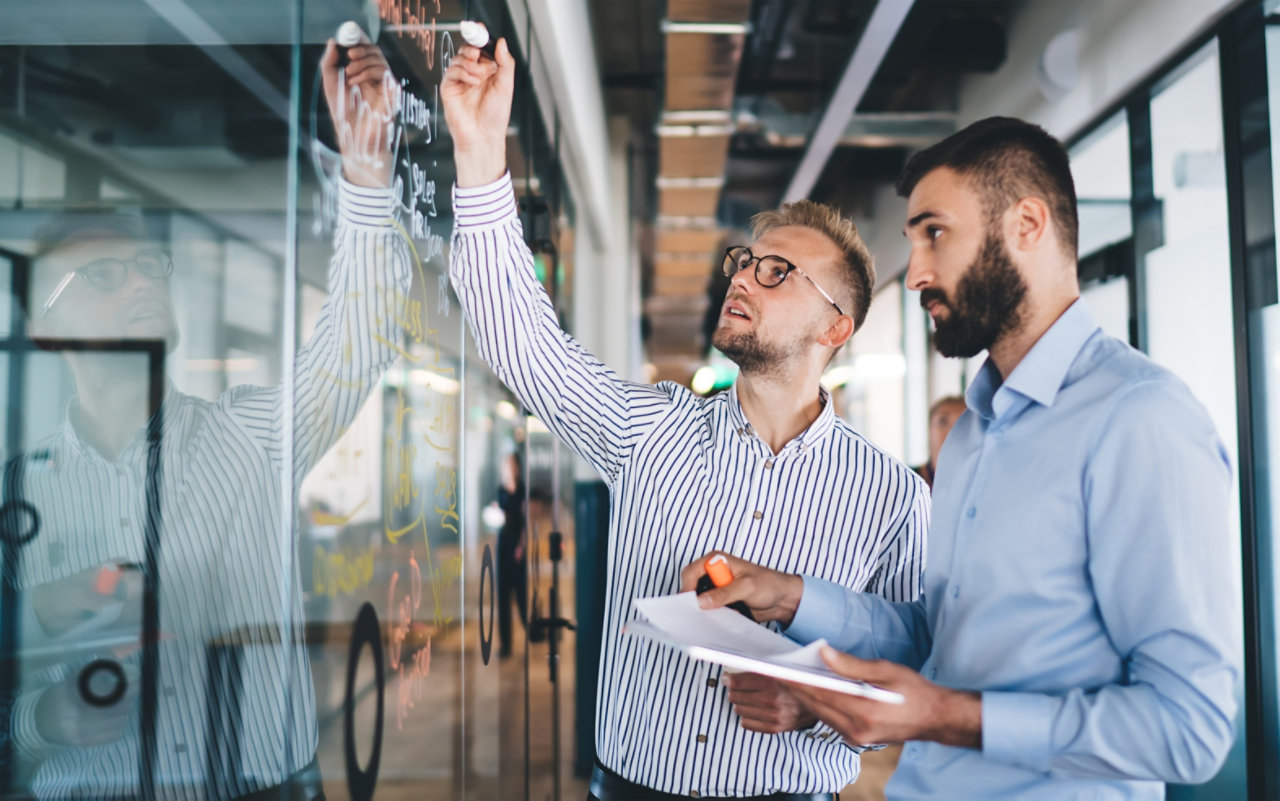 male colleagues writing on wall at work