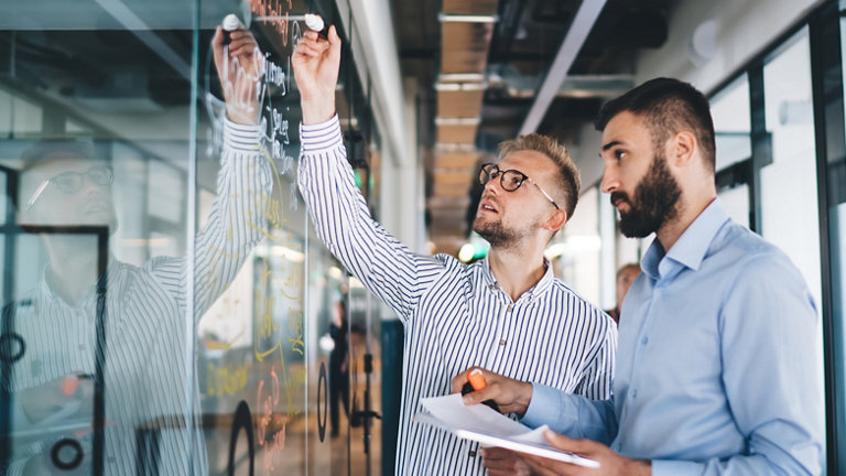 male colleagues writing on wall at work