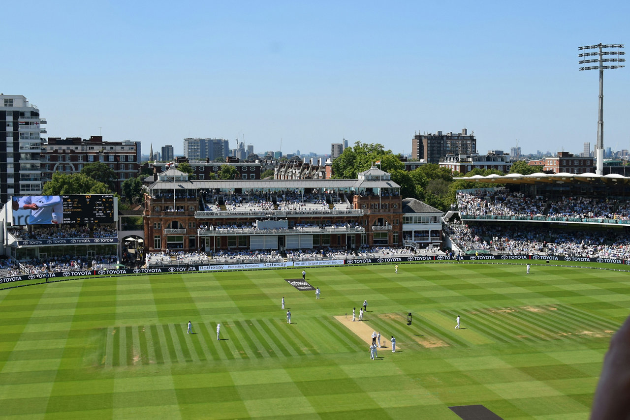 a cricket match is underway at a sunny stadium