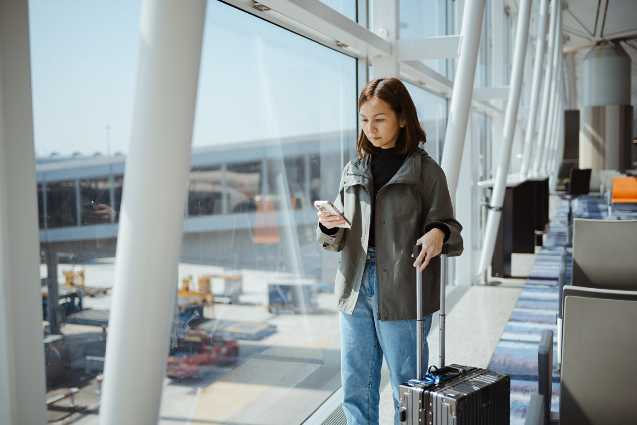 woman using phone whilst travelling through airport