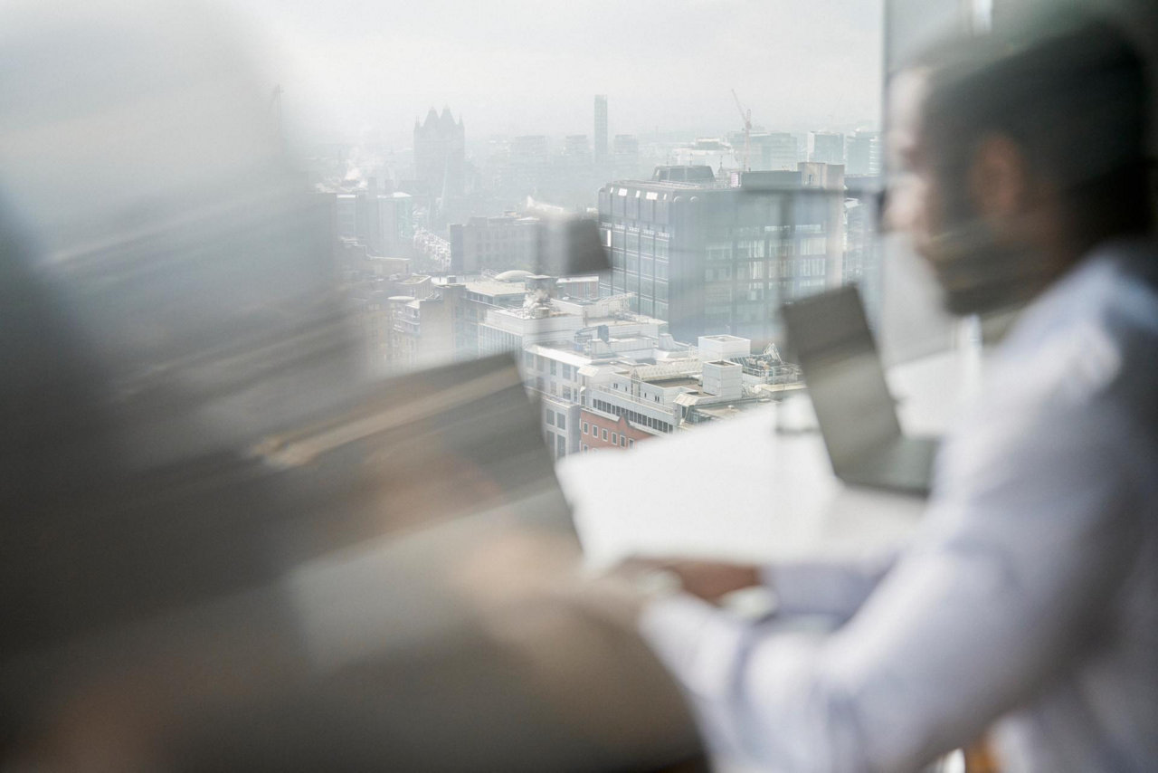 blurred city view with office worker in high rise using a laptop