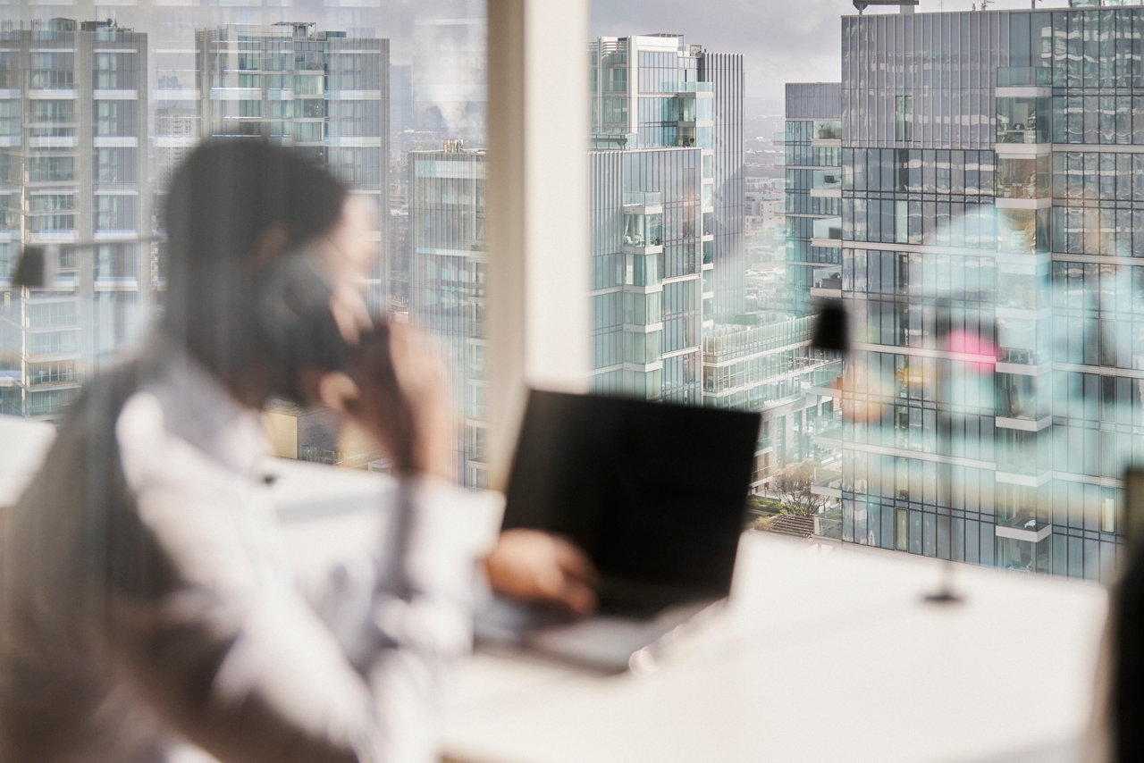 person on a laptop at an office window on a device