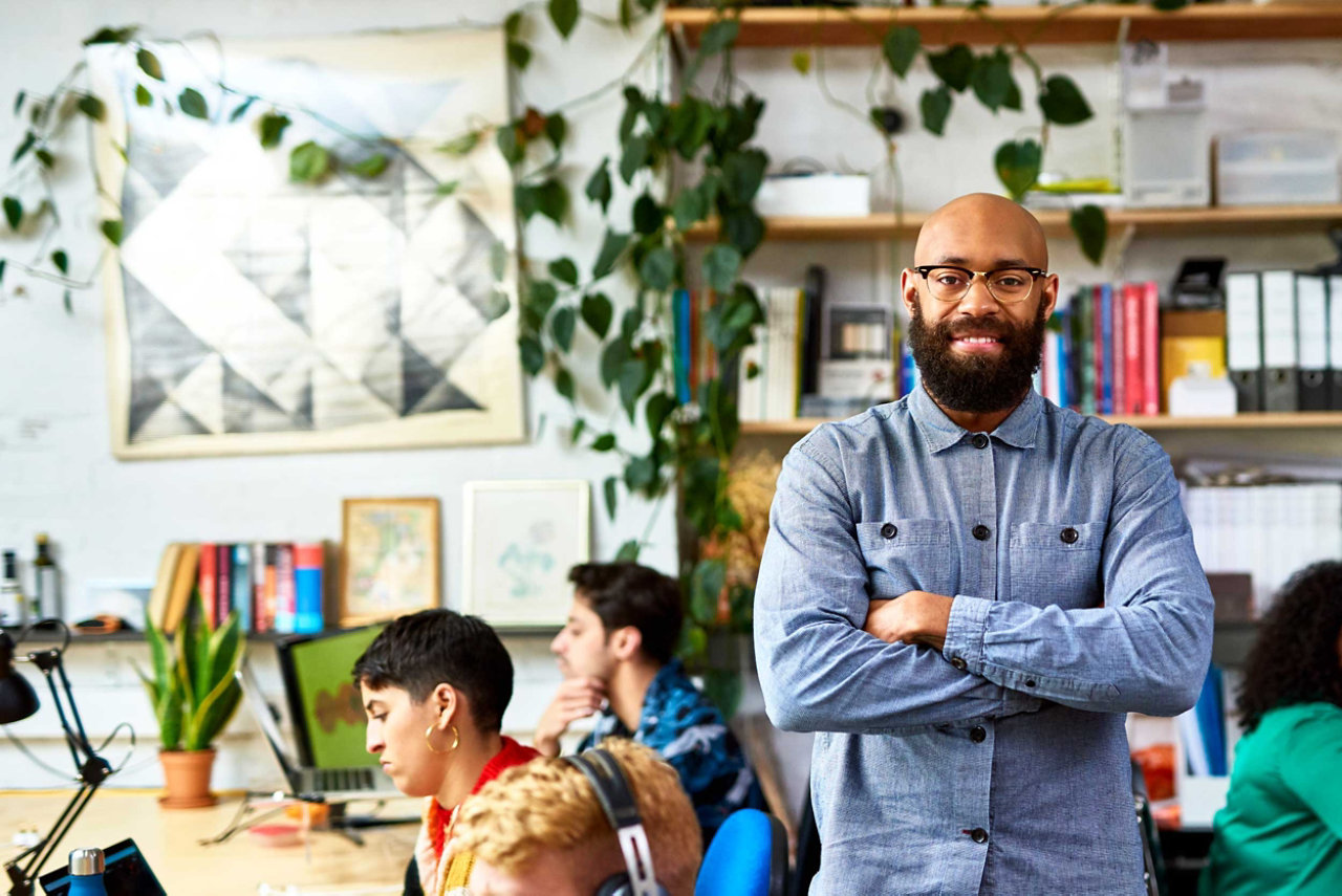 Small business owner standing in office with their team connected with BT Cloud Work