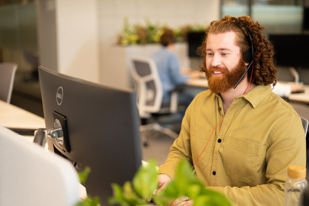 smiling man with two people working on commputer in office