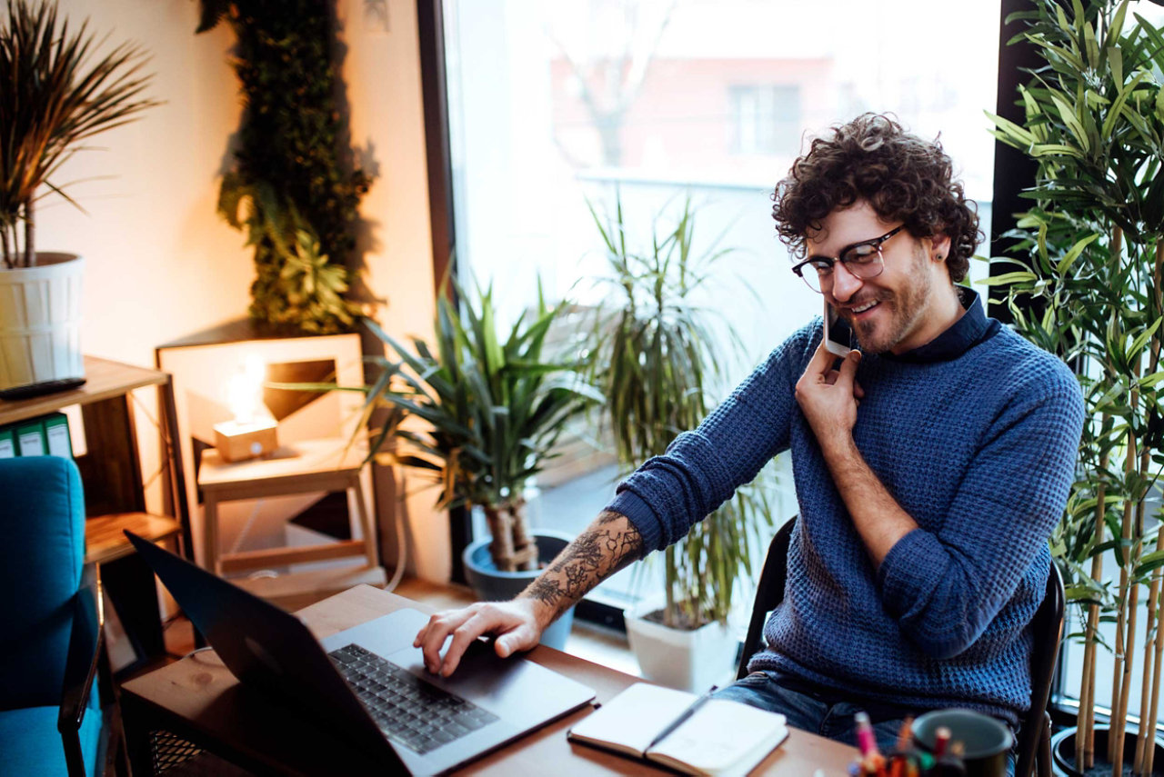 man using phone and looking at computer