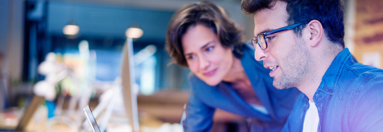 woman and man co-workers at desk talking