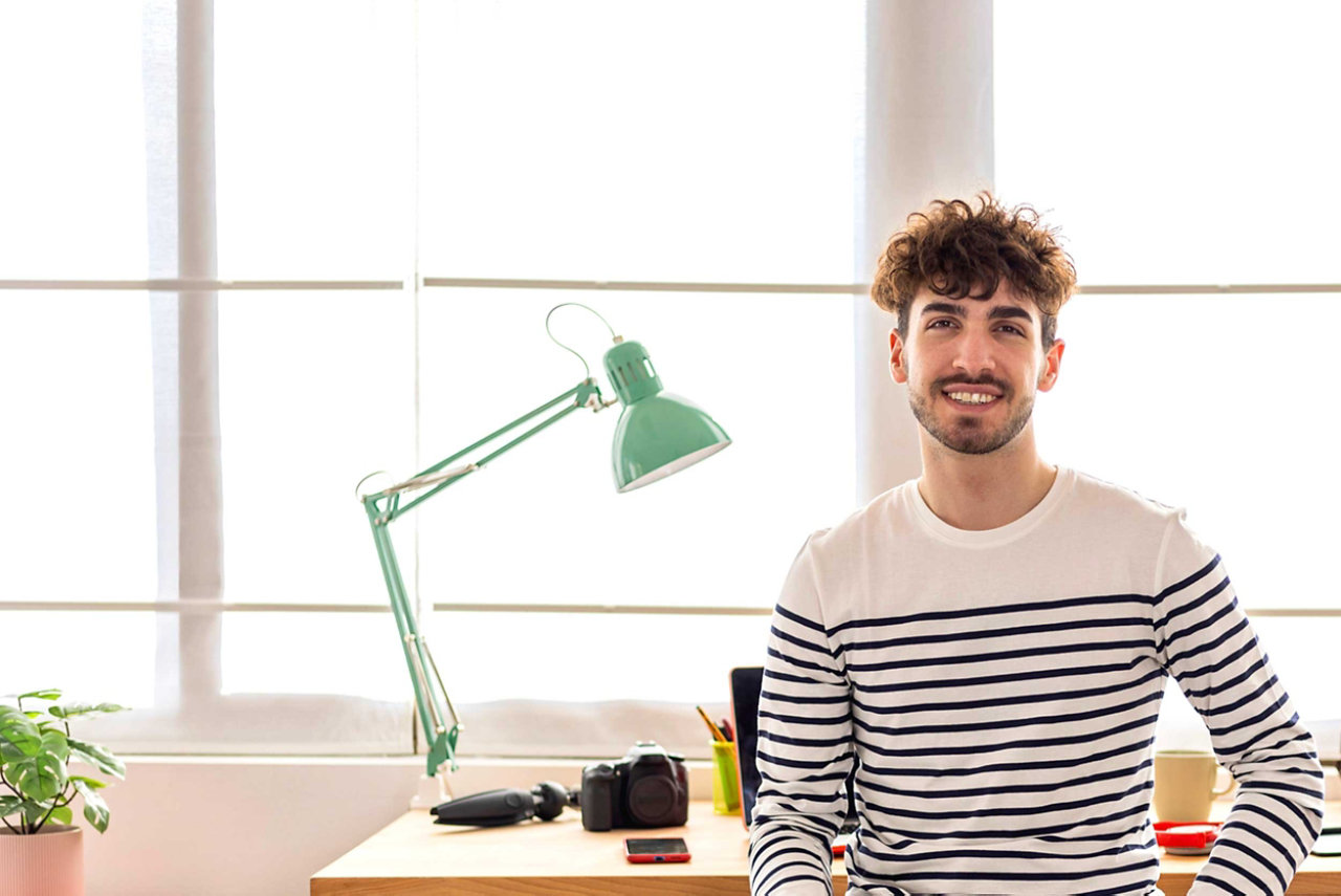 Man sitting in office at desk with lamp in background