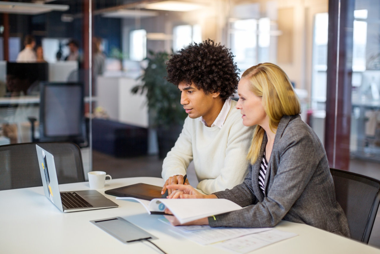 Businessman and businesswoman using laptop computer. Male and female business professional working together in modern office.