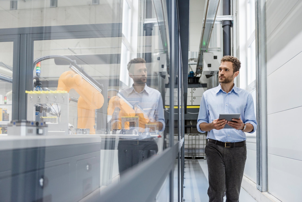 business person checking robots in a factory