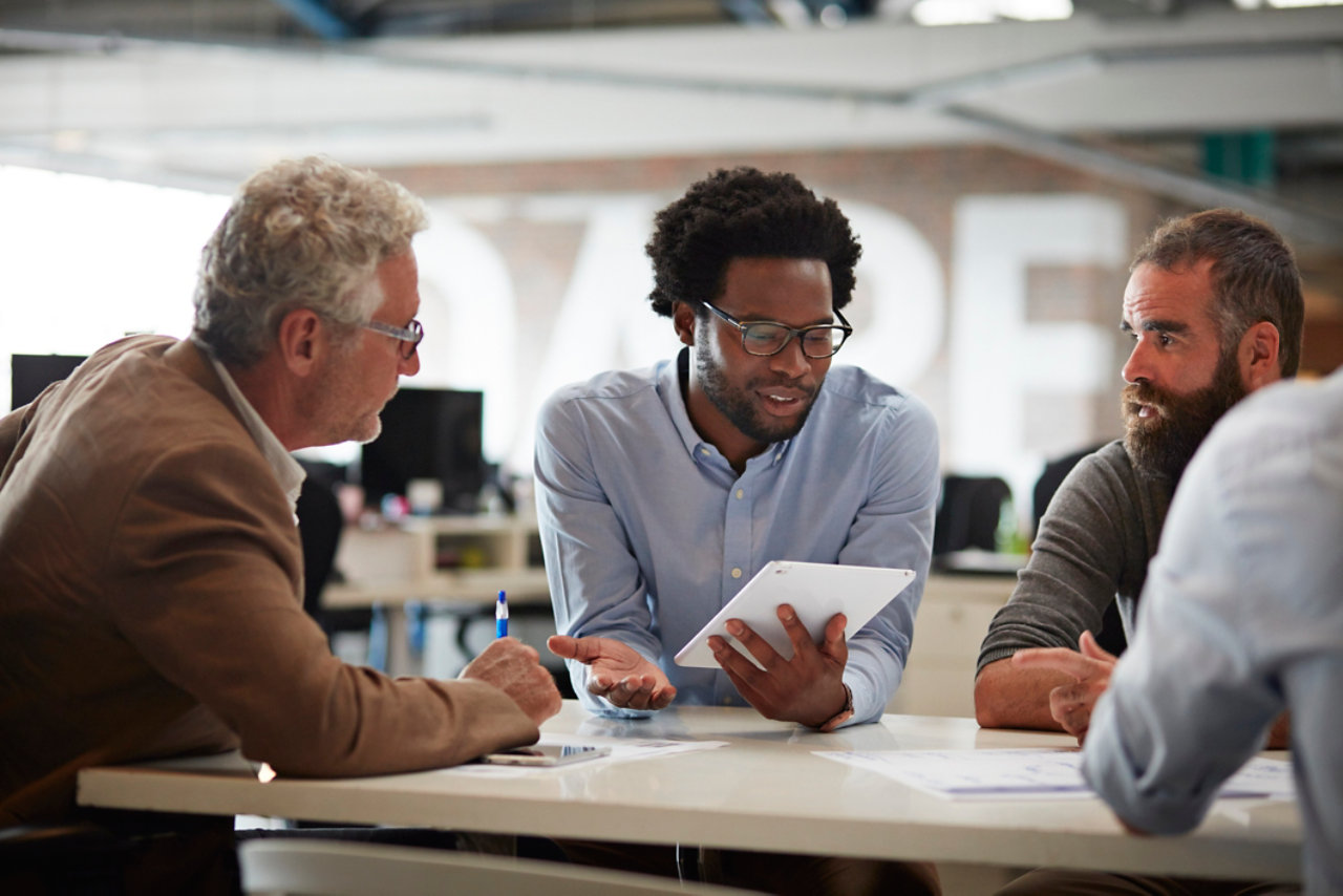 businessman presenting to co-workers with tablet