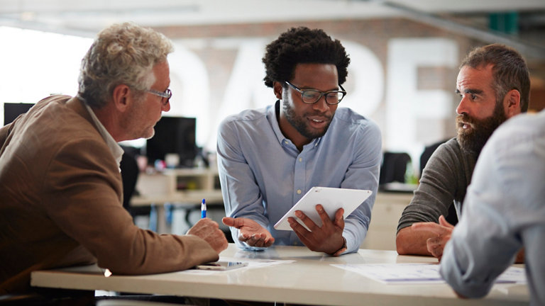 businessman presenting to co workers with tablet