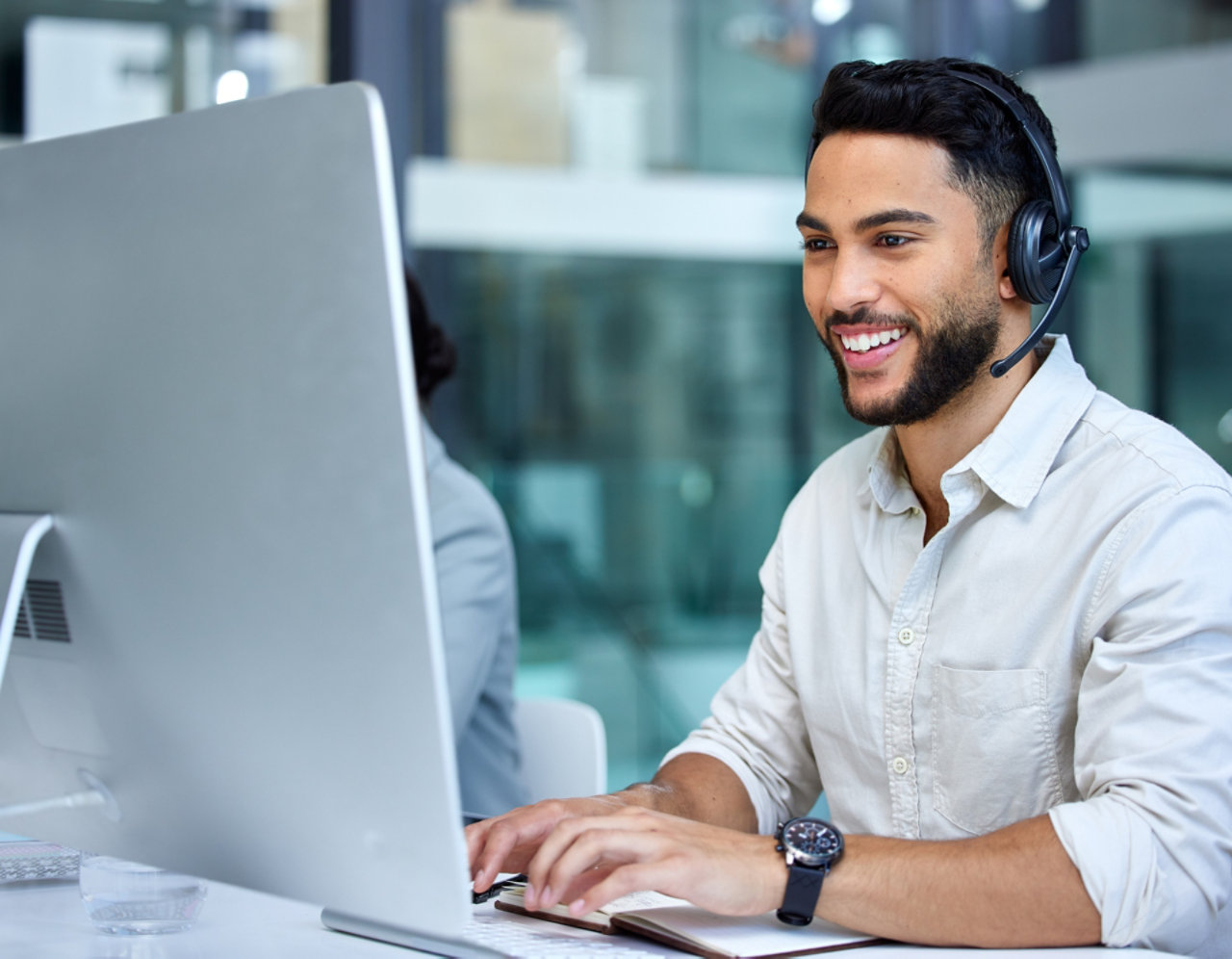 smiley man with headset in front of large screen