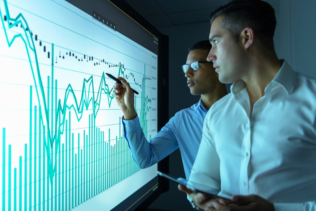 two men looking at graphs on a screen