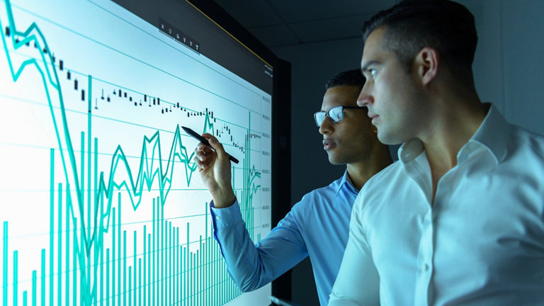 men looking at graphs on an interactive screen