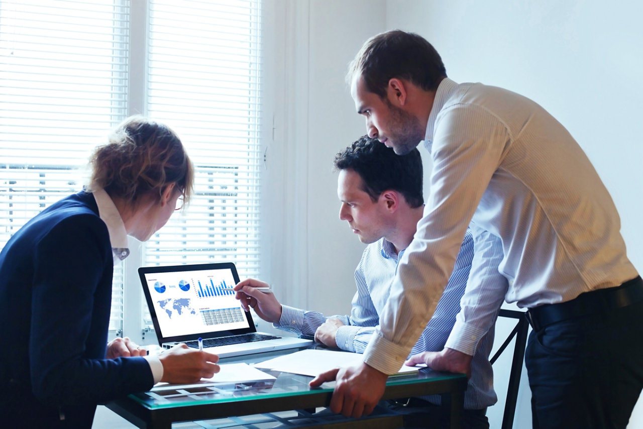 people in an office around a latop