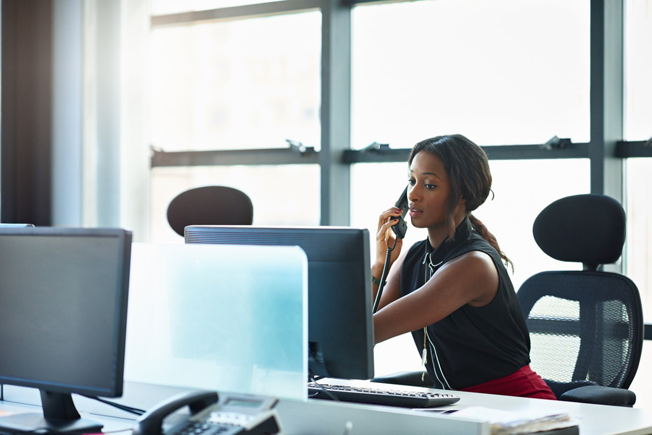 multitaking woman on phone and computer at desk