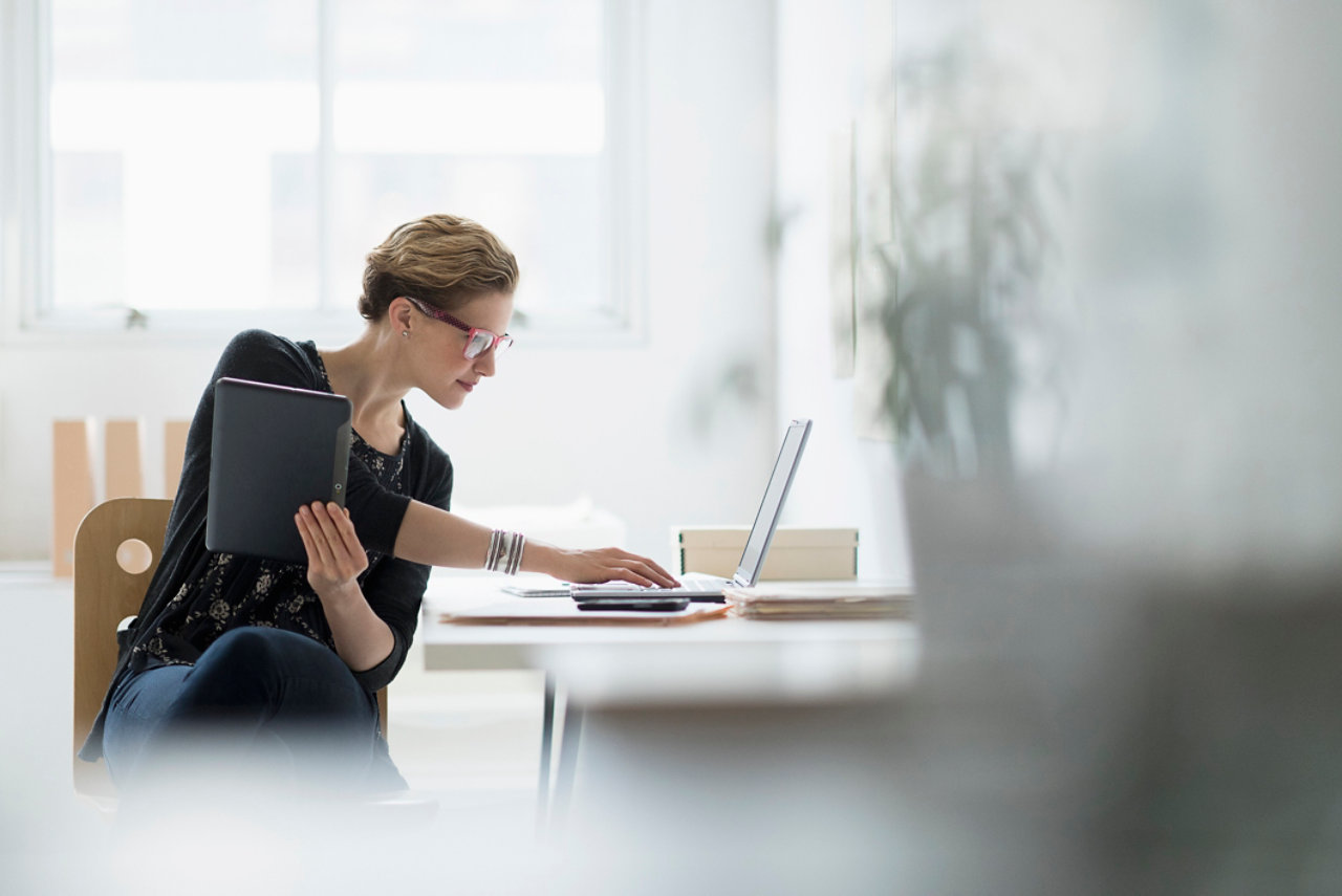 woman with glasses working on laptop