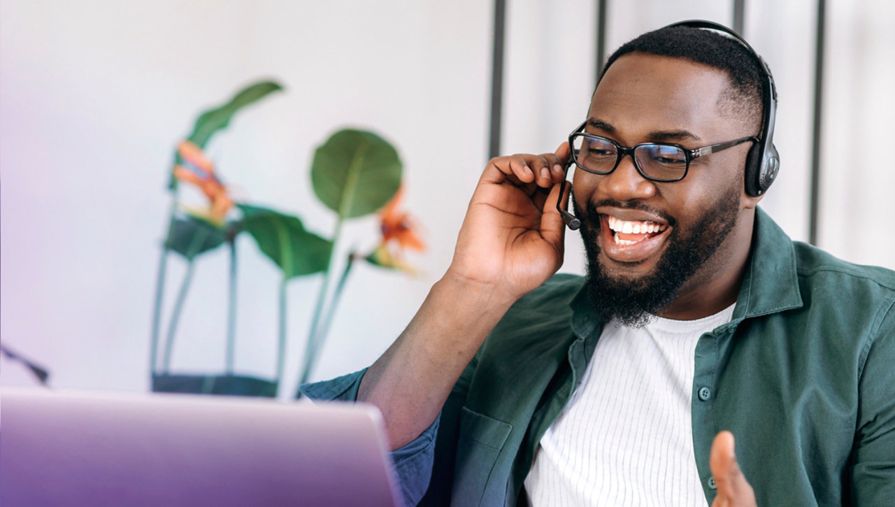 seated man with headset talking looking at laptop