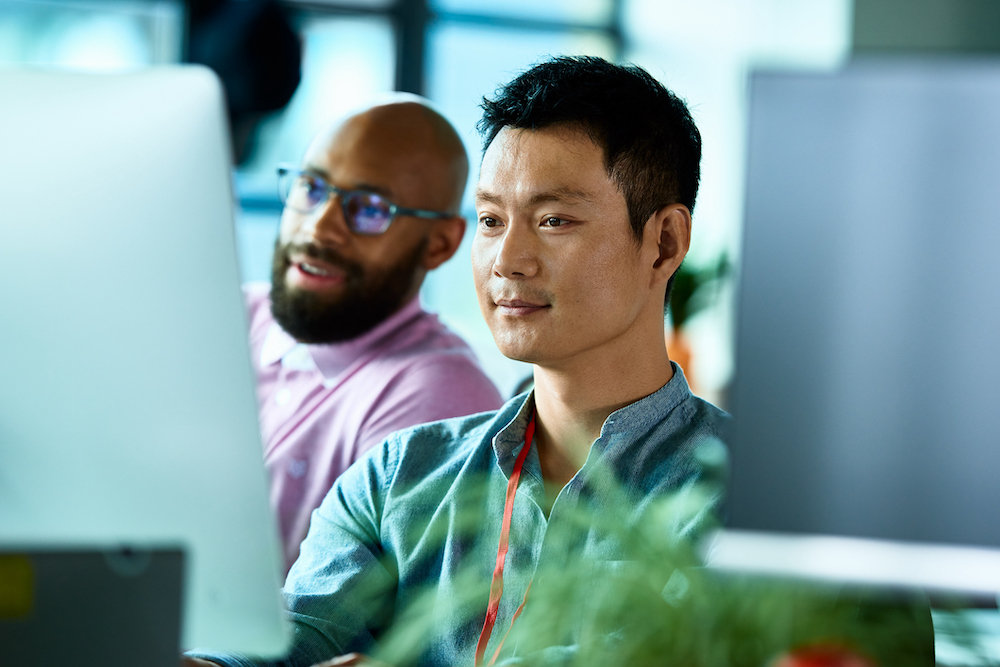 chinese office worker at desktop computer with colleague