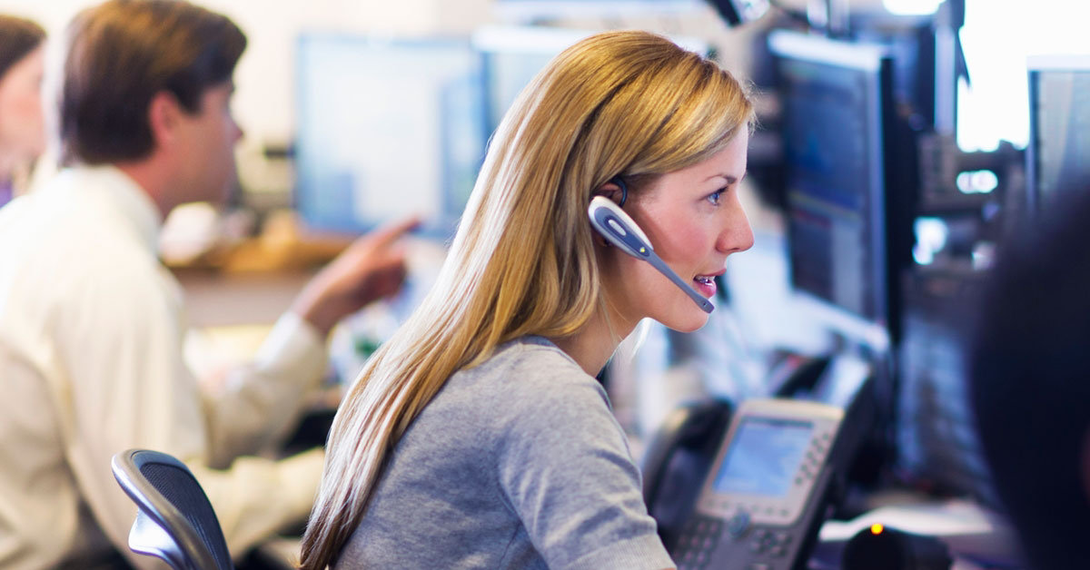 woman in headset in call centre blurred background man colleague