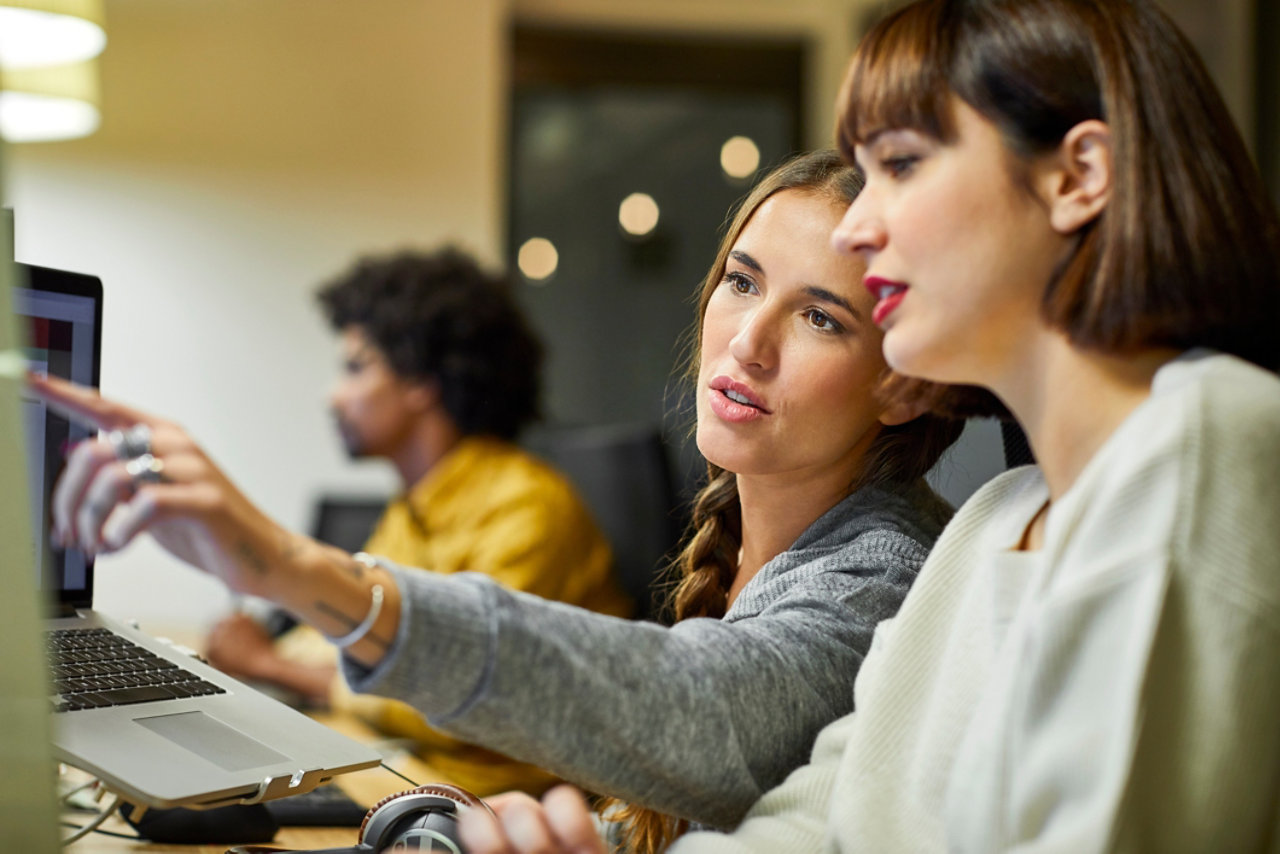 Coworkers discussing over computer in office