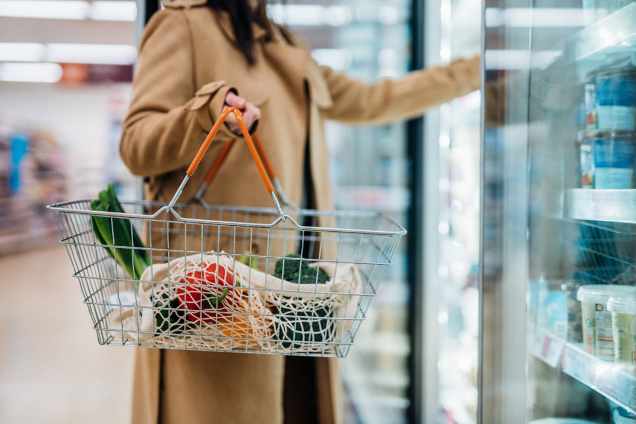 Cropped shot of woman carrying shopping basket and shopping groceries in supermarket