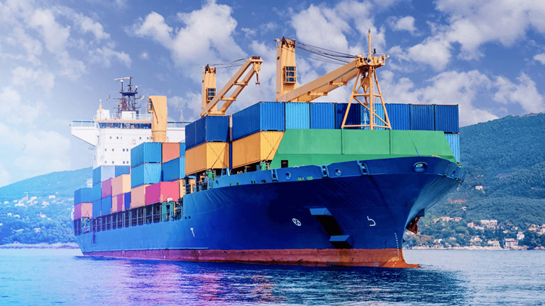 container ship on water with fields in background