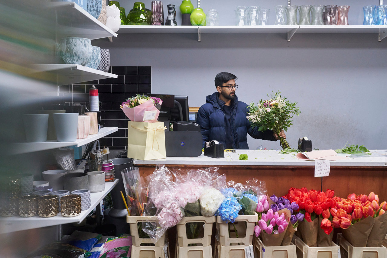 florist with flowers behind till