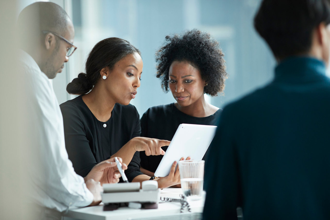 group of coworkers standing arounddesk and having meeting