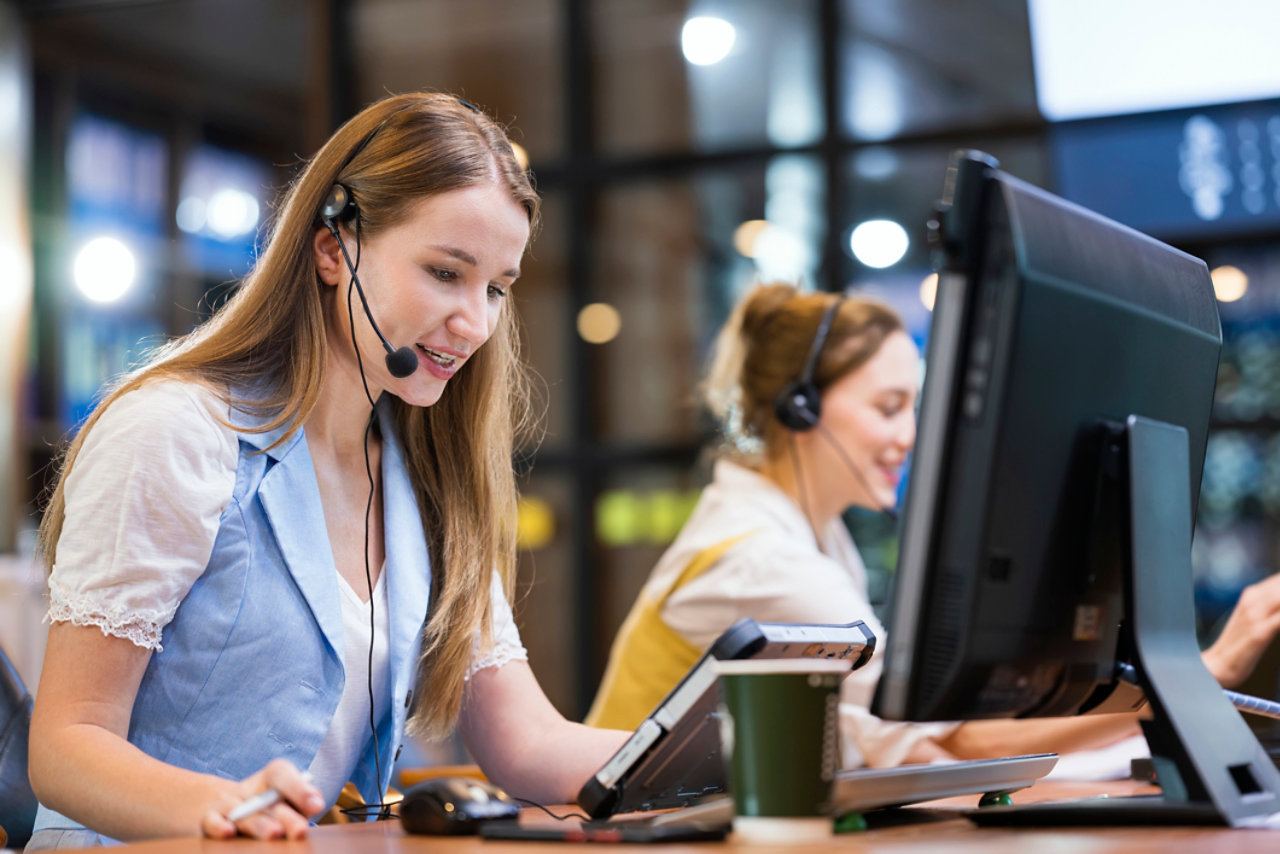 seated women at work stations using tablet and screen