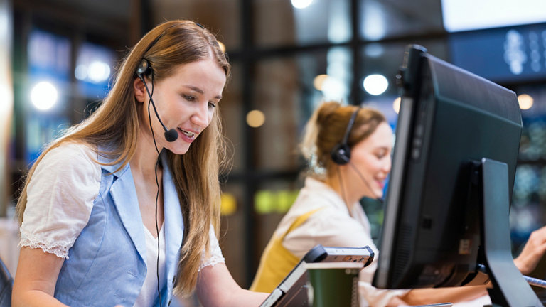 seated women at work stations using tablet and screen