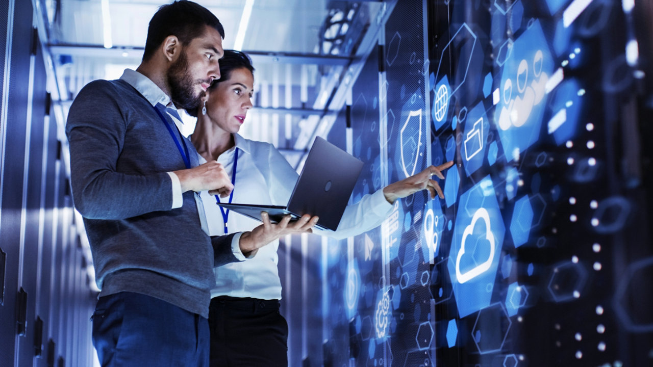 man and woman co-workers standing and pointing in digital room