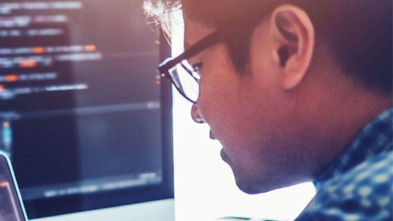 man looking at big computer screen