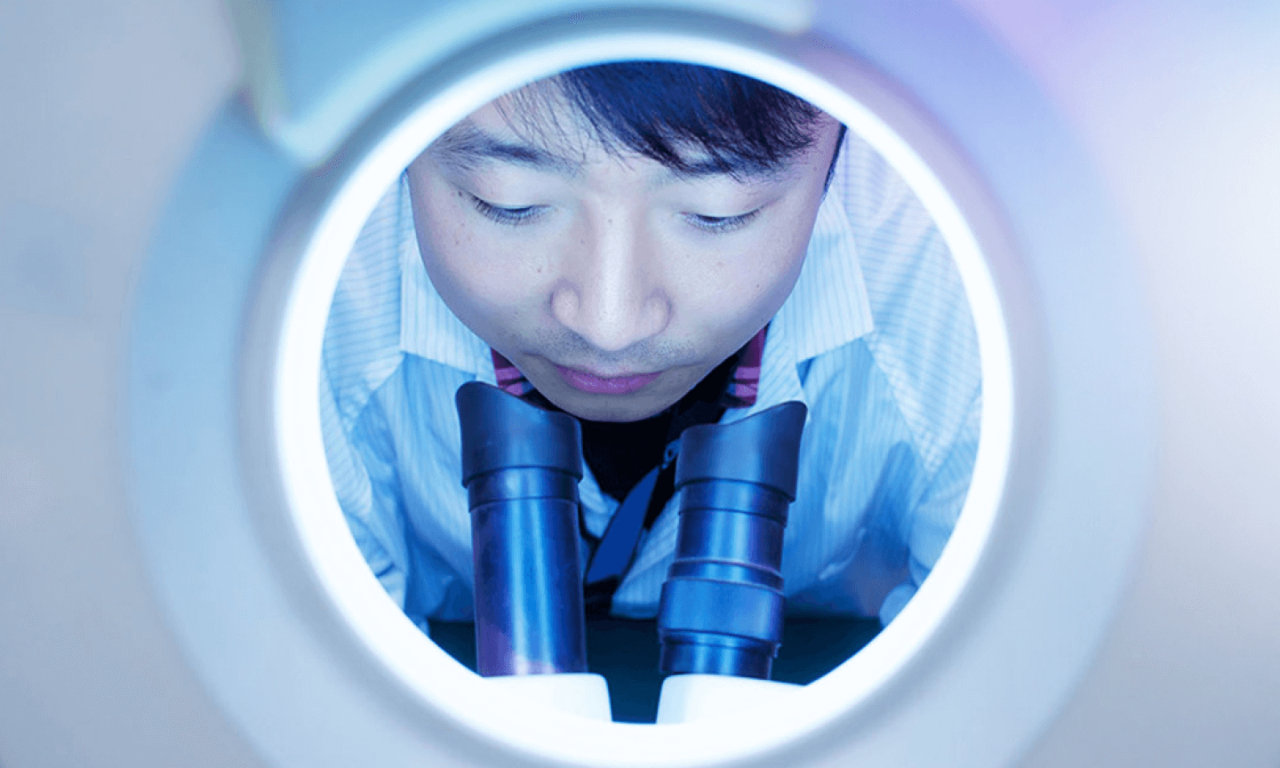 man looking through microscope