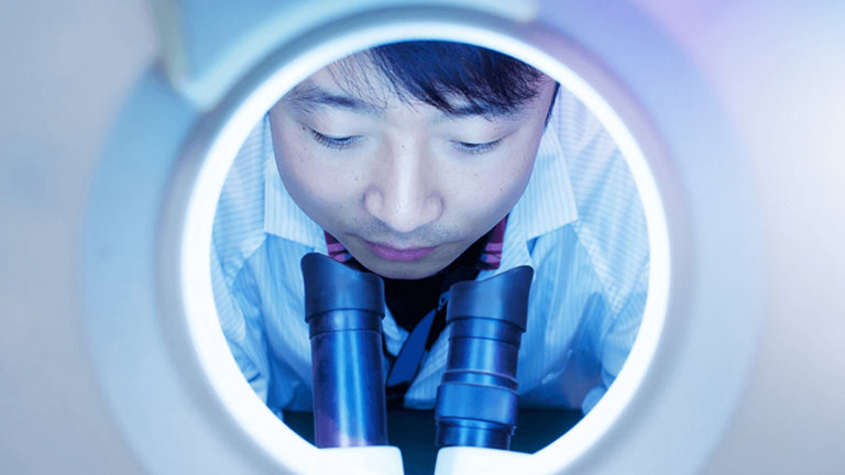 man looking through microscope