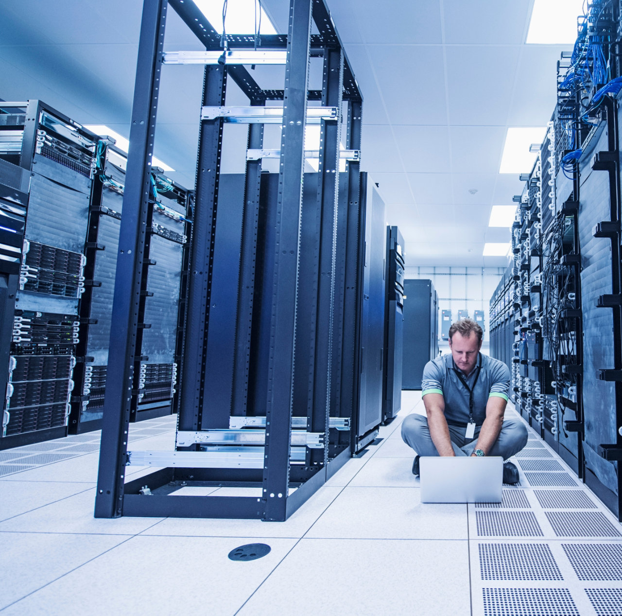 Man sitting on floor and using laptop in server room