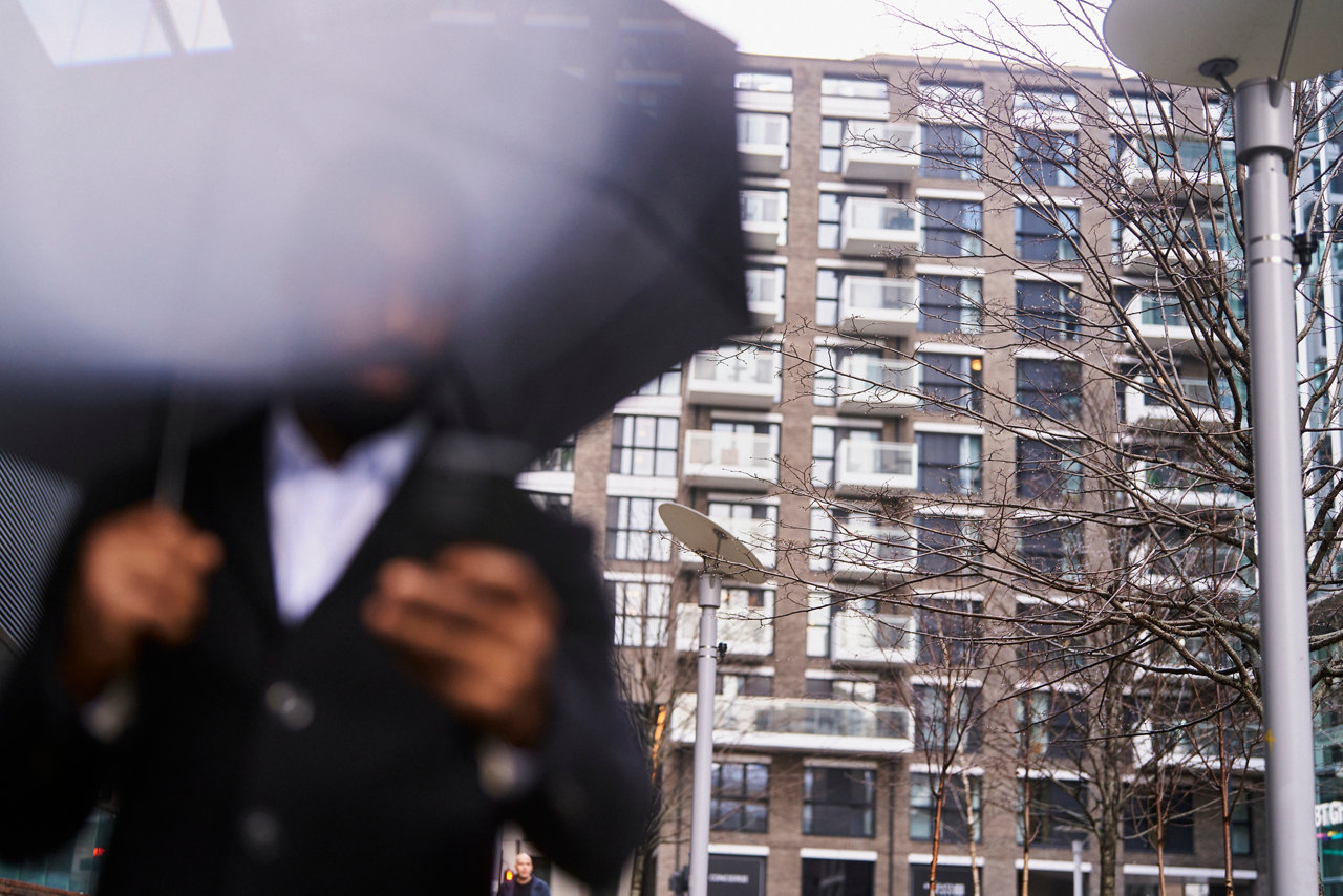 person with umbrella looking at phone with city backdrop