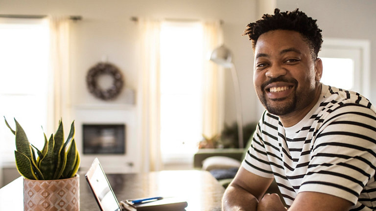 man working from home smiling at desk