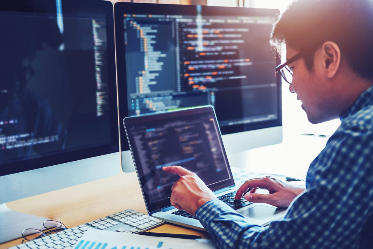 man coding on laptop on desk