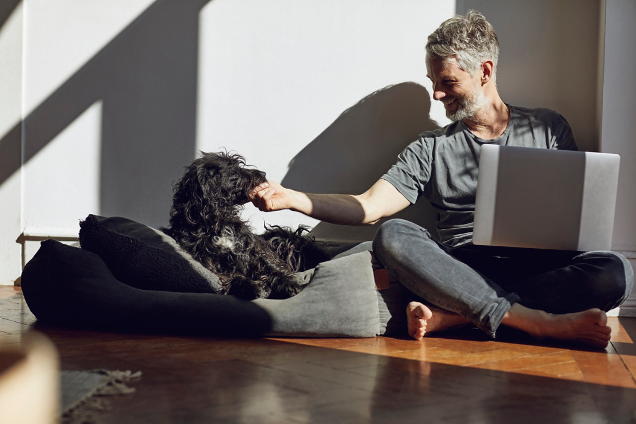 Mature man sitting on the floor at home with laptop