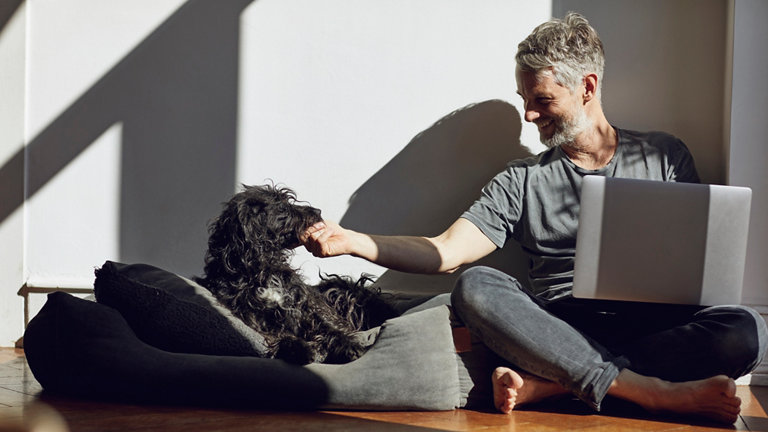 Mature man sitting on the floor at home with laptop