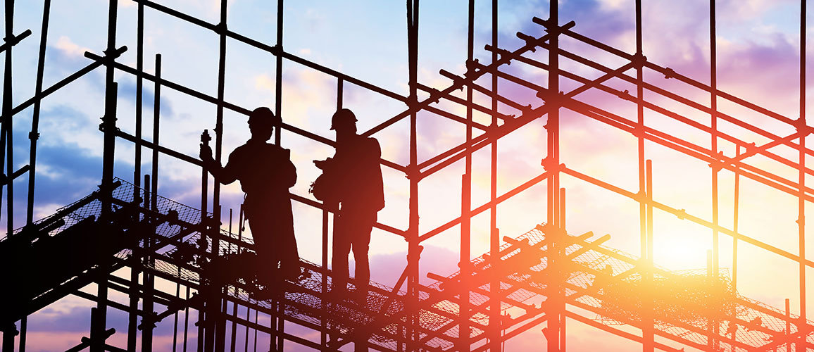 Men on scaffolding with sunset background