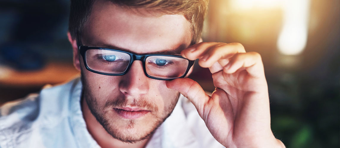 A man with glases looking at a computer screen