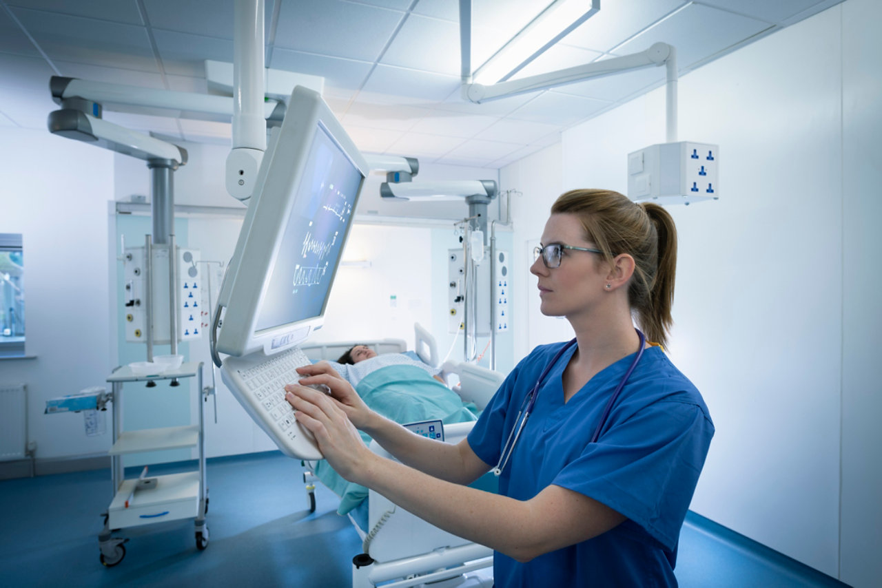 Nurse inspecting screen in intensive care unit