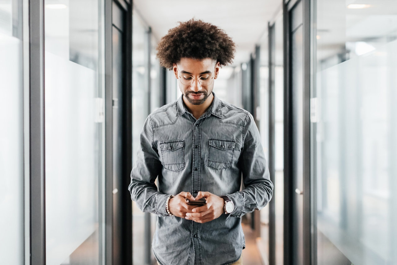 Man walking down corridor using smartphone