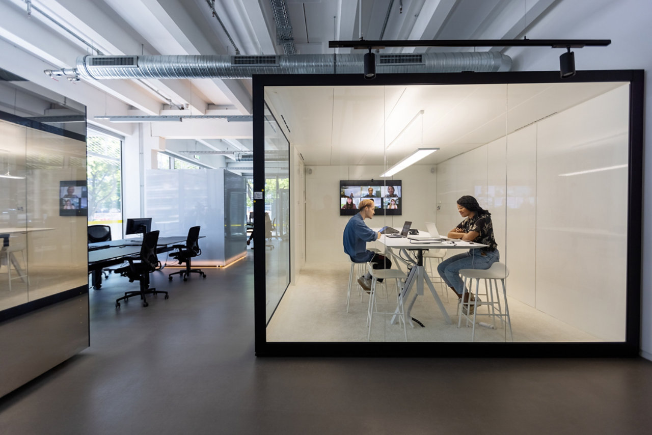 people talking in glass-walled office