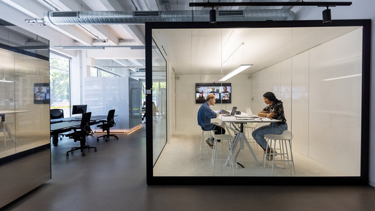 people talking in glass-walled office